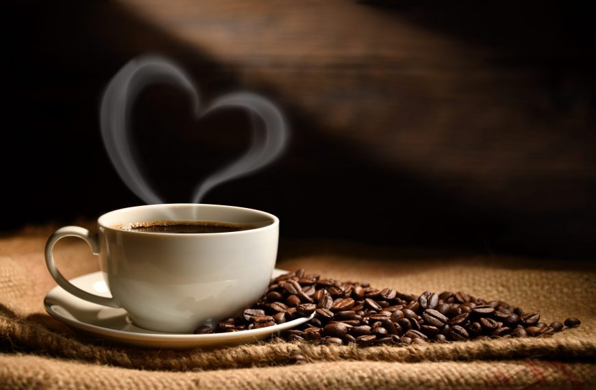 Cup of coffee with heart shape smoke and coffee beans on burlap